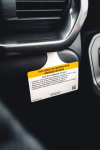 Detailed view of a car airbag safety warning label inside a vehicle. Vue détaillée d'une étiquette d'avertissement de sécurité airbag automobile à l'intérieur d'un véhicule.