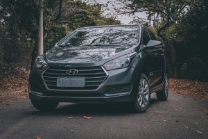 Elegant black Hyundai car parked on a scenic road surrounded by trees, showcasing a modern automotive design. Une élégante voiture Hyundai noire garée sur une route panoramique entourée d'arbres, mettant en avant un design automobile moderne.