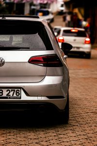 A silver car with visible taillights parked on a city street. Une voiture argentée avec des feux arrière visibles garée dans une rue de la ville.