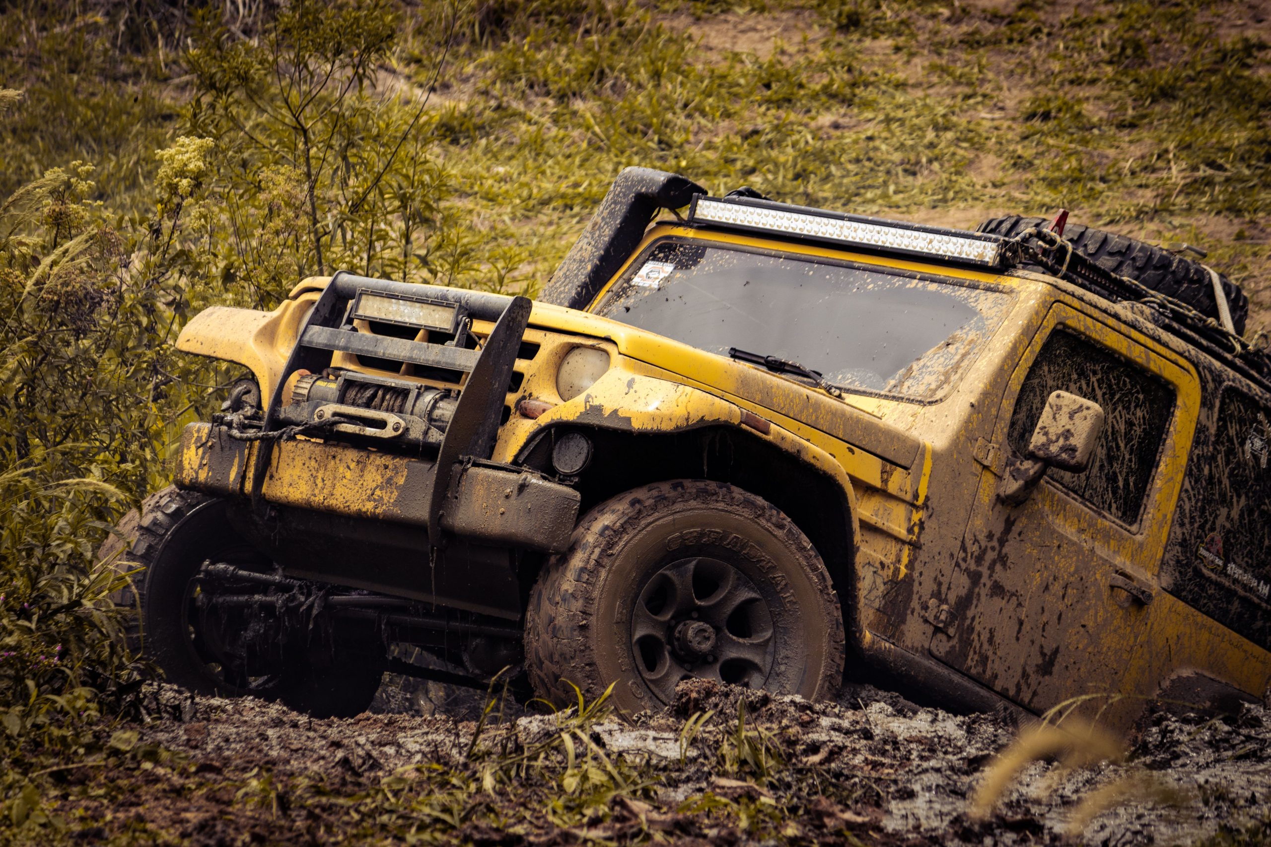 SUV 4x4 jaune franchissant chemin boueux