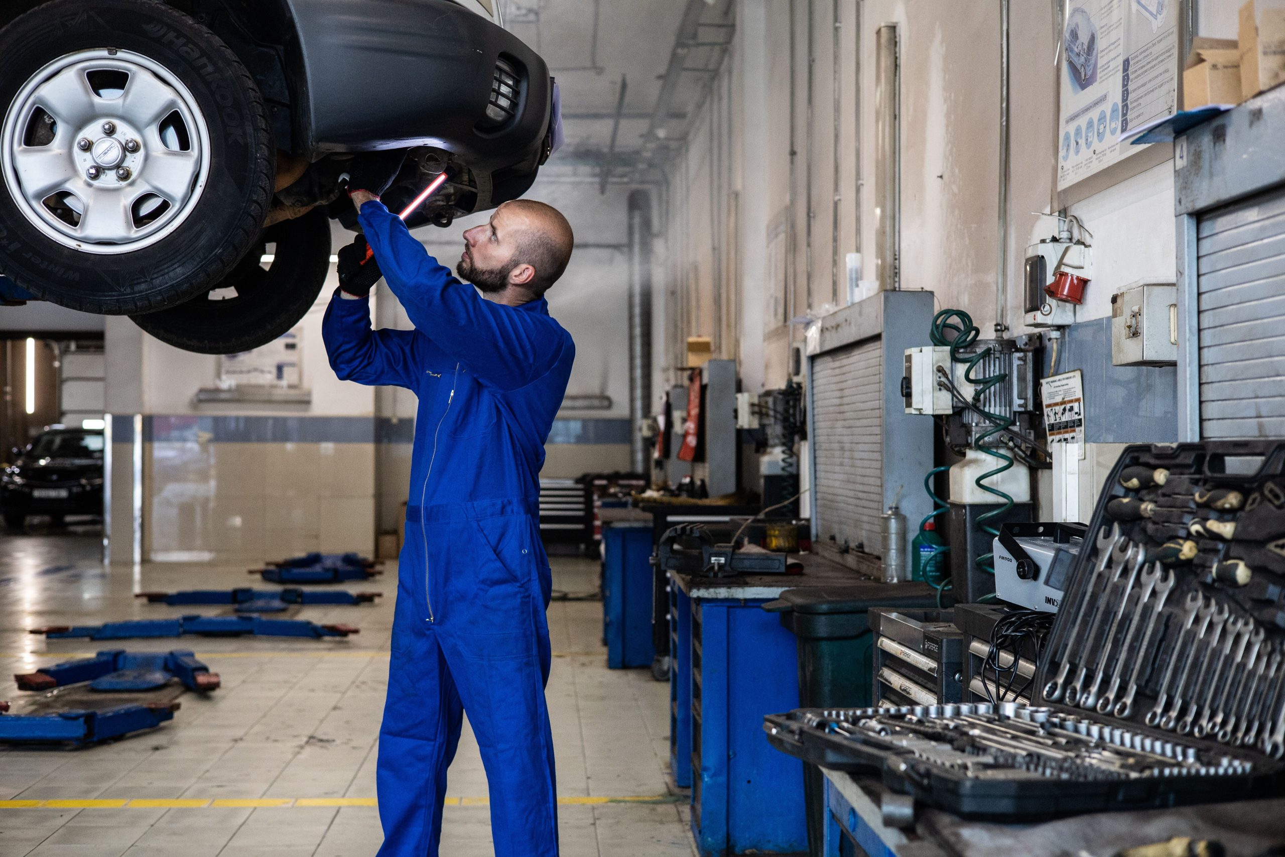 Mécanicien inspectant une voiture soulevée en atelier