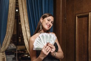 Femme glamour tenant un éventail d'argent liquide