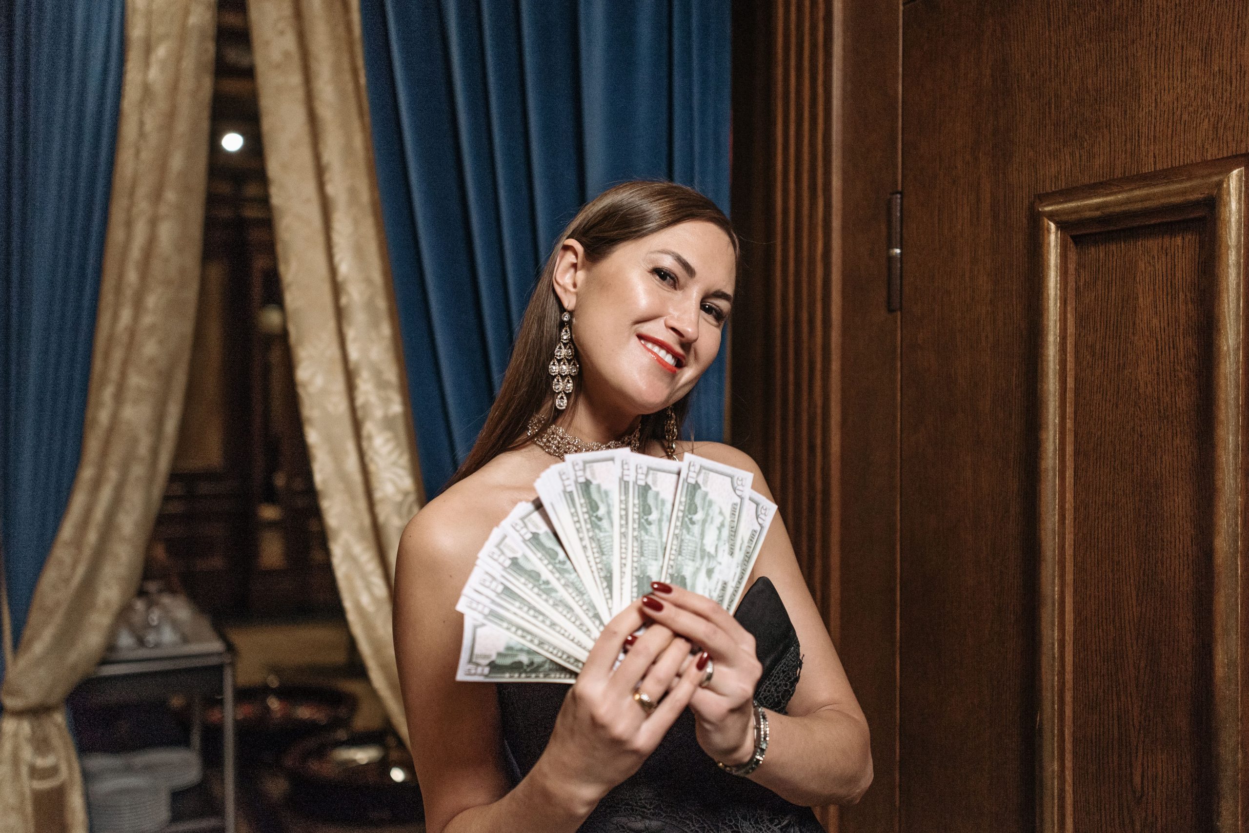 Femme glamour tenant un éventail d'argent liquide