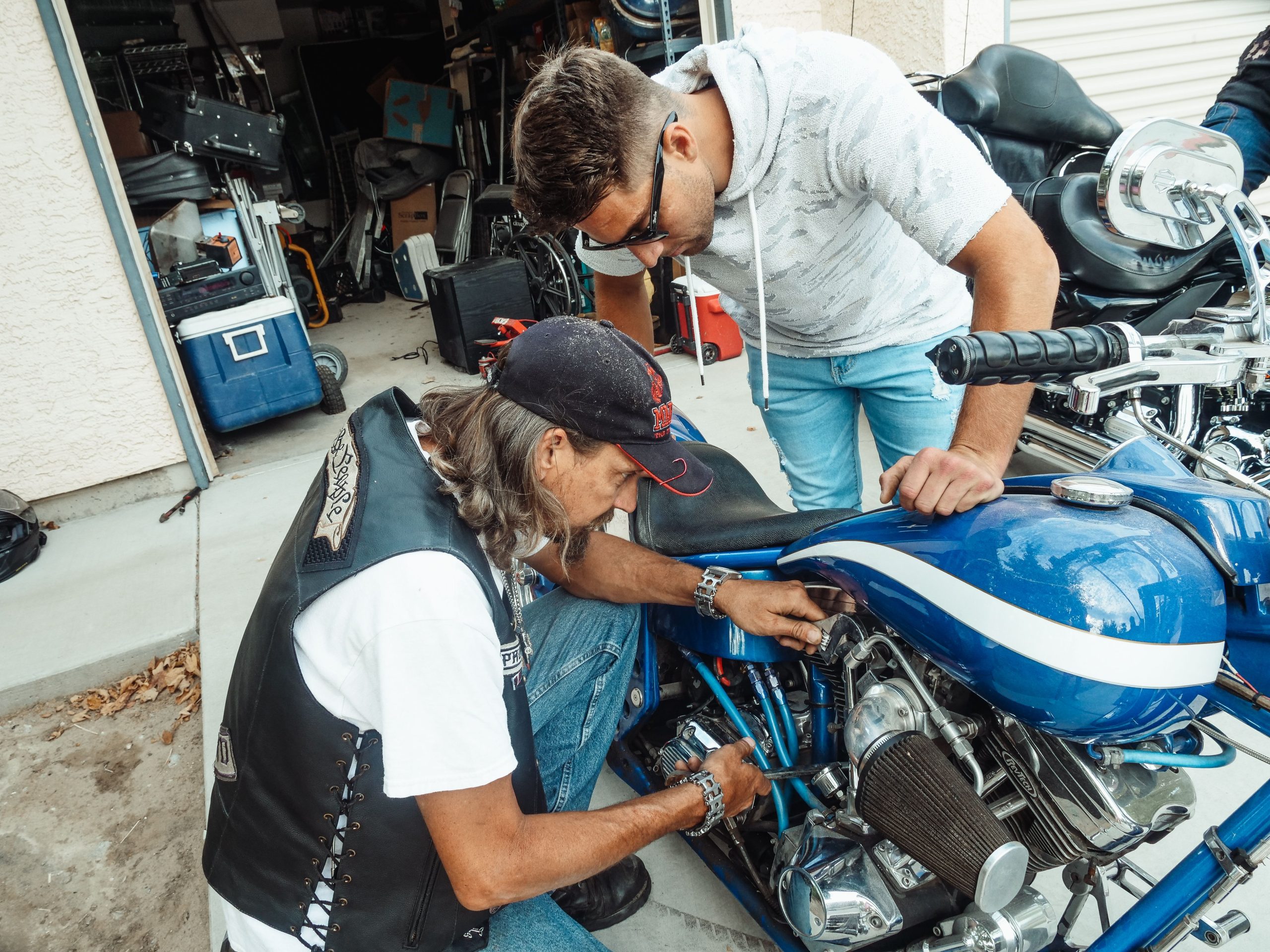 Deux hommes réparent une moto bleue en garage