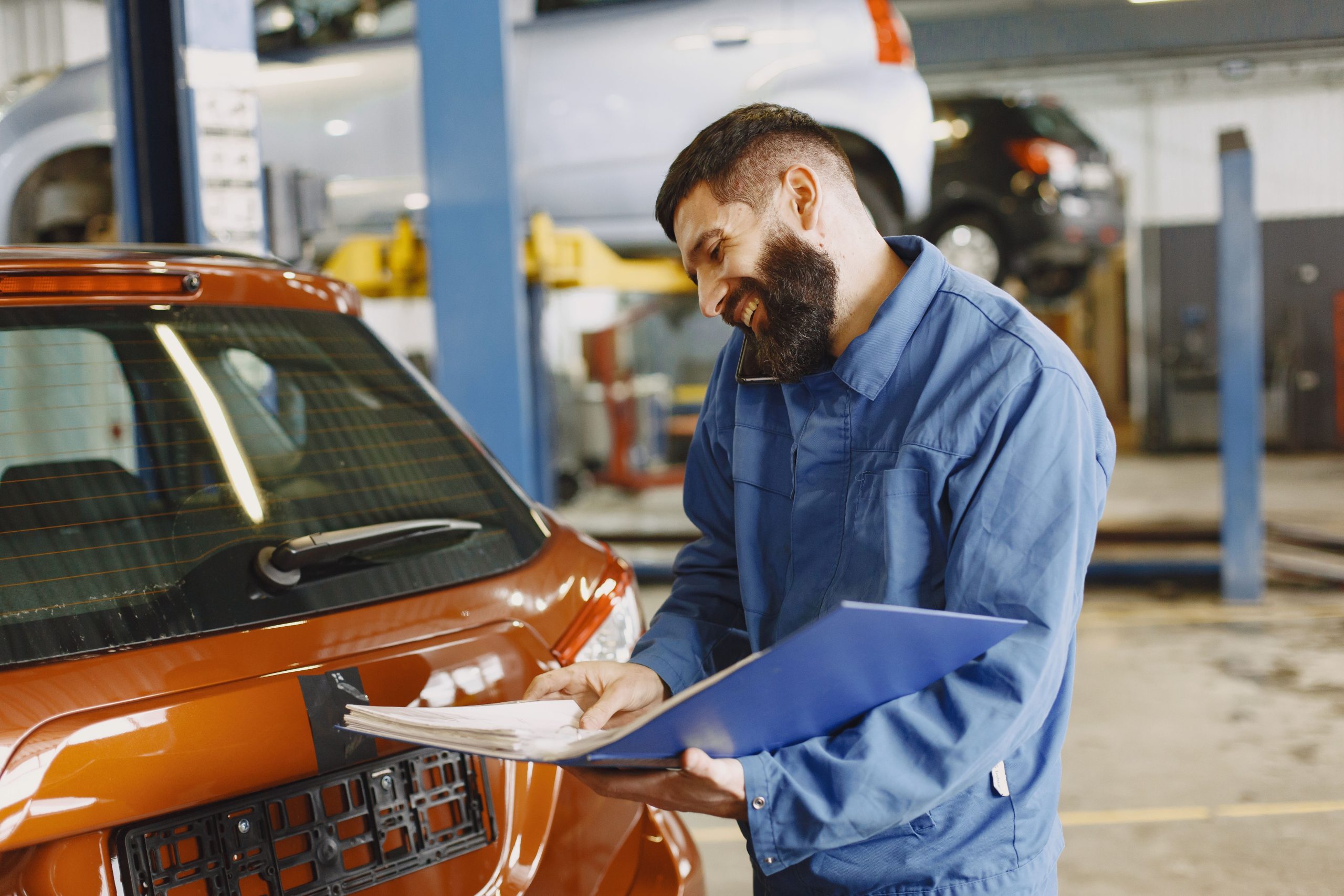 Mécanicien souriant vérifie une voiture en atelier