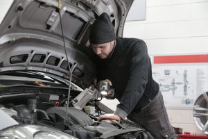 Mécanicien inspectant moteur voiture en garage
