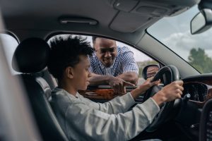 Jeune garçon au volant avec père instructeur dehors