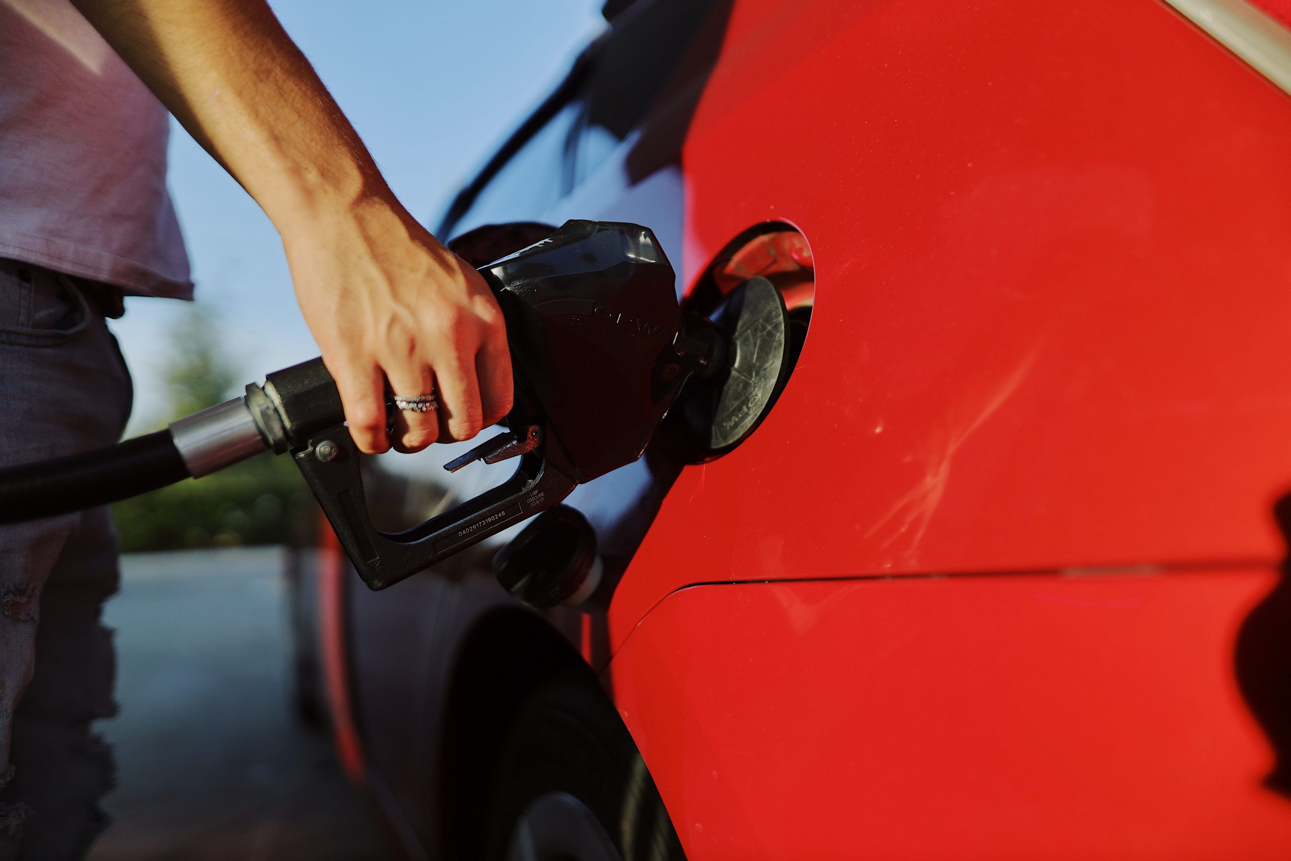Personne ravitaillant une voiture rouge à la station-service