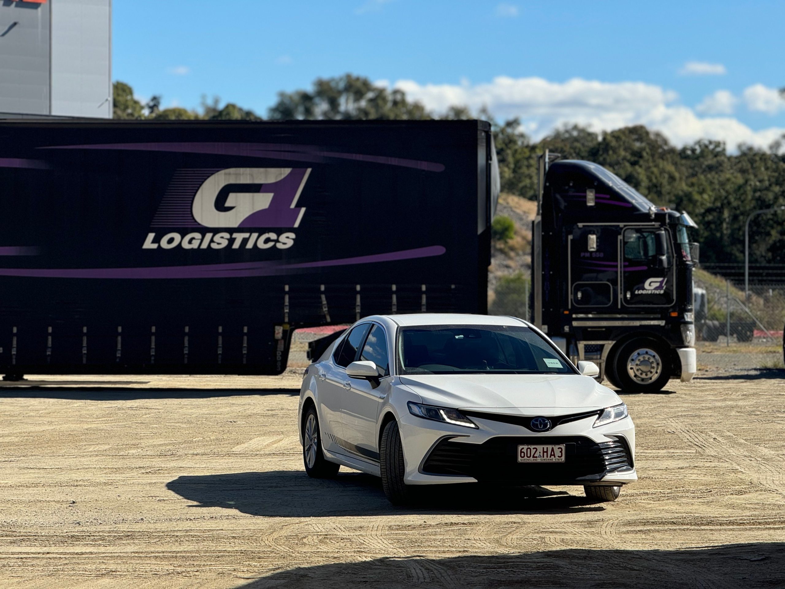 Berline blanche garée devant un camion de logistique