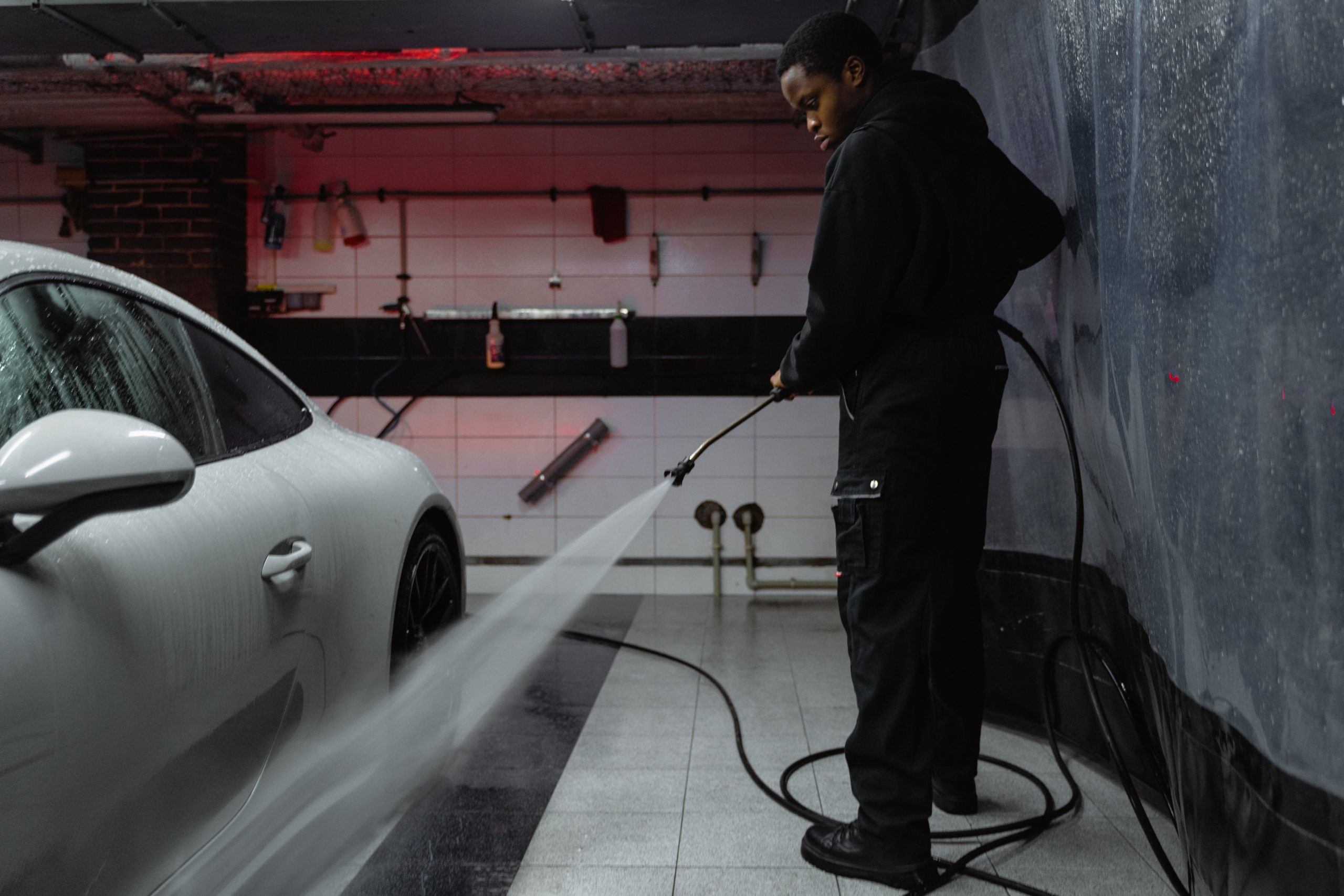 Homme nettoyant voiture blanche au jet haute pression